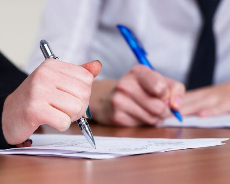 due persone che scrivono su un foglio per una consulenza grafologica aziendale